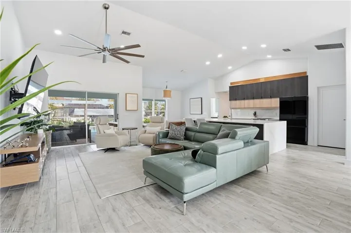 Living room with a ceiling fan, light wood-style flooring, vaulted ceiling, and recessed lighting