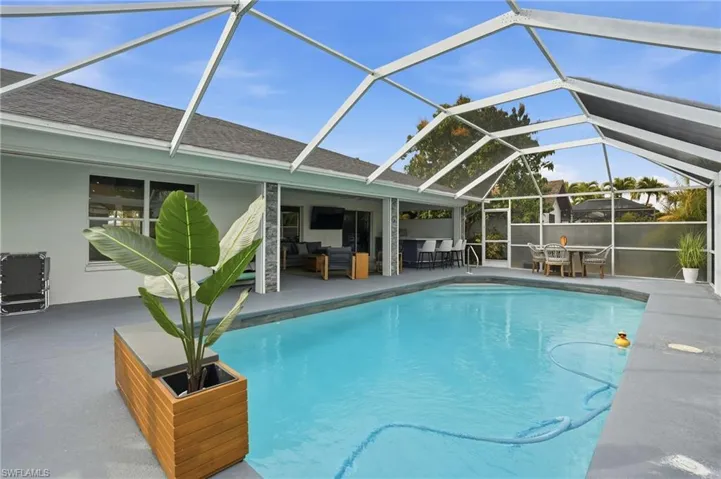 Outdoor pool featuring glass enclosure, an outdoor living / dining area, a sunroom, and a patio area