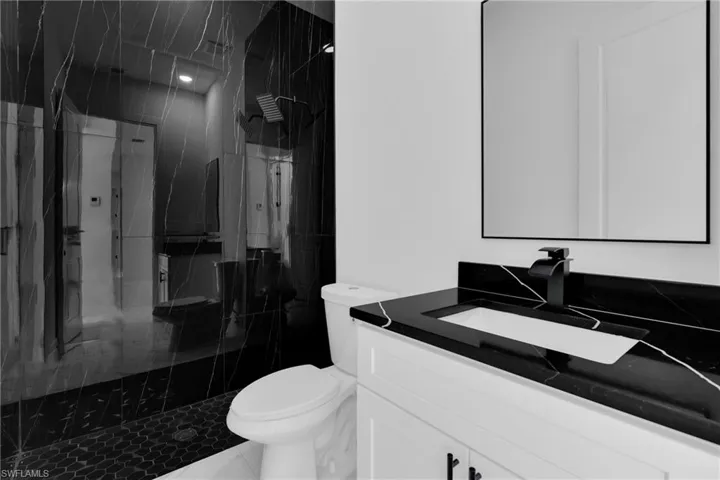 Full bath featuring a marble finish shower and vanity