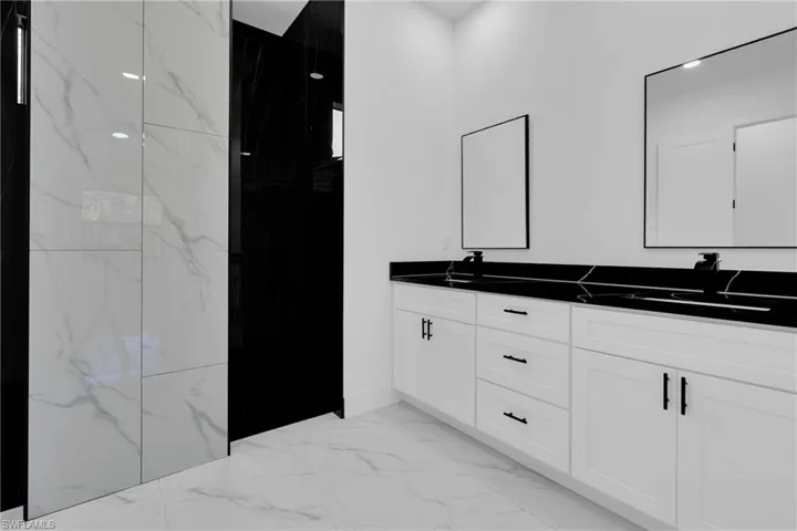 Full bathroom with double vanity and a marble finish shower