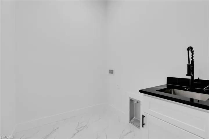 Washroom with hookup for a washing machine and light marble finish floors
