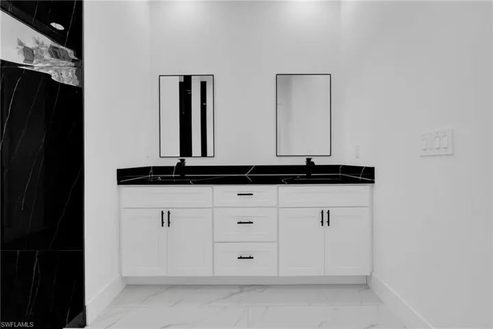 Full bath featuring double vanity and a marble finish shower