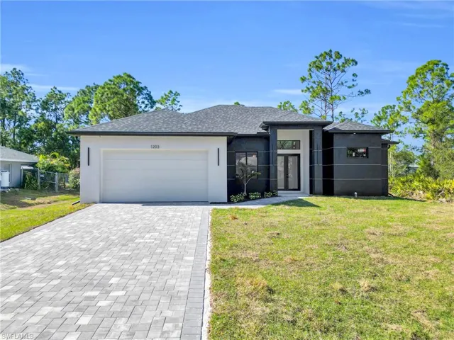 Prairie-style house featuring stucco siding, decorative driveway, a front lawn, and a garage