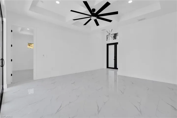 Empty room with recessed lighting, light marble finish floors, a tray ceiling, ceiling fan, and french doors