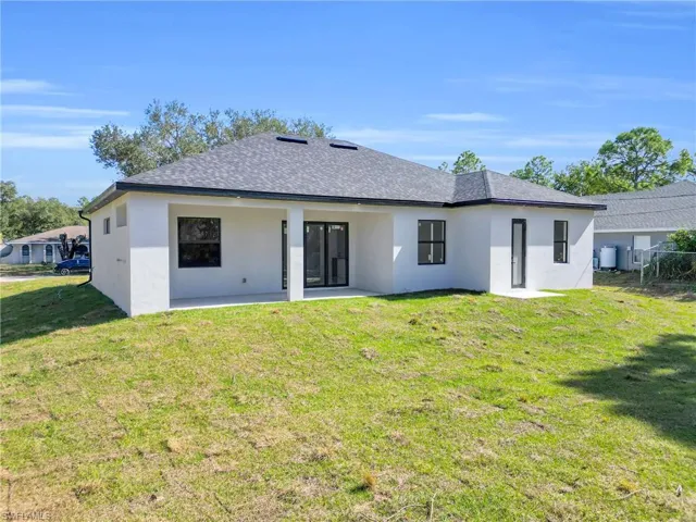 Back of property with stucco siding, a patio area, and roof with shingles