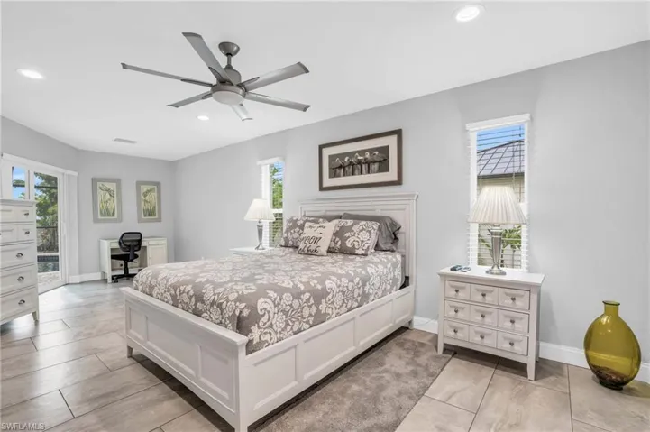 Tiled bedroom featuring multiple windows, access to outside, and ceiling fan