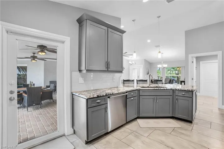 Kitchen featuring tasteful backsplash, kitchen peninsula, dishwasher, ceiling fan with notable chandelier, and gray cabinets
