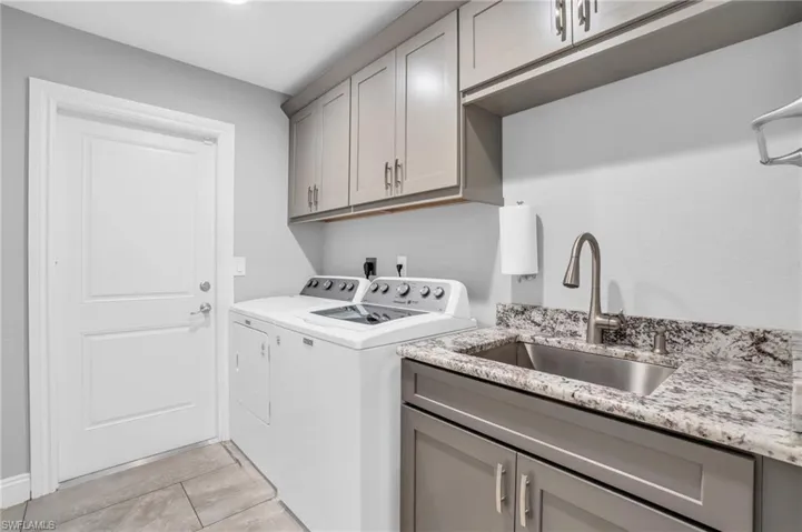 Washroom featuring cabinets, light tile patterned floors, washing machine and dryer, and sink