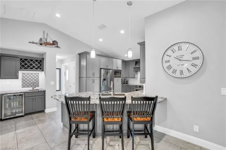 Dining space with sink, wine cooler, vaulted ceiling, and light tile patterned floors