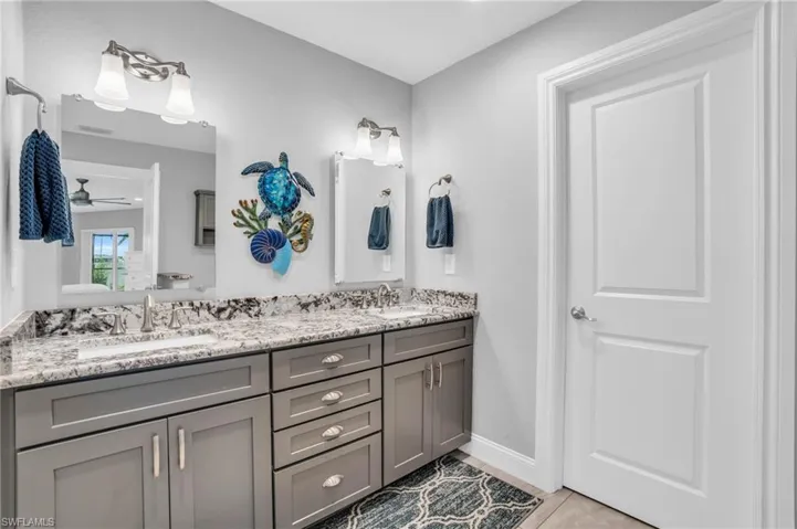 Bathroom featuring dual vanity, tile patterned floors, and ceiling fan