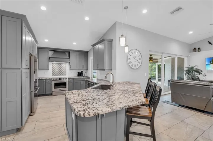 Kitchen featuring pendant lighting, decorative backsplash, sink, custom range hood, and gray cabinetry