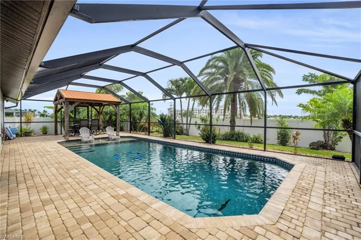 View of pool with a patio, pool water feature, and glass enclosure