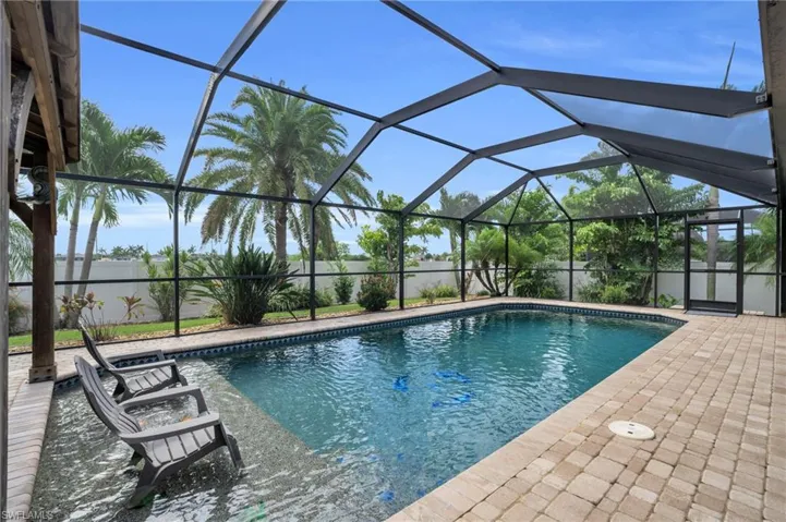 View of pool with a patio and glass enclosure