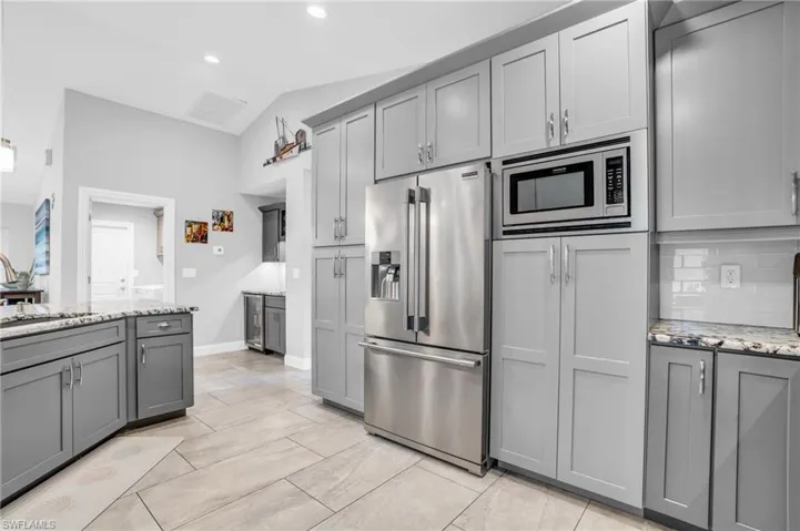 Kitchen with stainless steel appliances, light stone countertops, light tile patterned floors, and backsplash