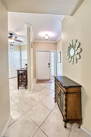 Foyer entrance featuring ornamental molding, light tile patterned flooring, and ceiling fan