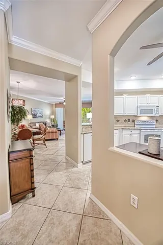 Hallway featuring light tile patterned flooring and crown molding
