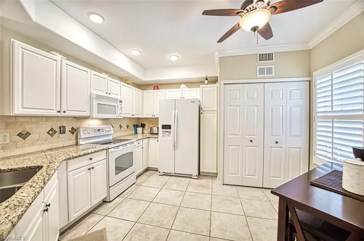 Kitchen featuring tasteful backsplash, white appliances, light tile patterned floors, and ceiling fan