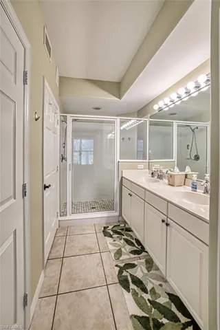 Bathroom with walk in shower, tile patterned flooring, and dual vanity