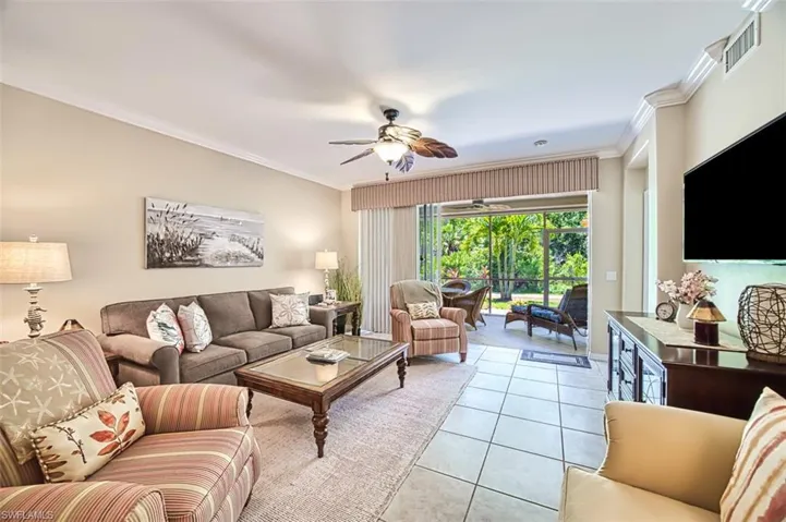 Living room featuring light tile patterned floors, ceiling fan, and crown molding