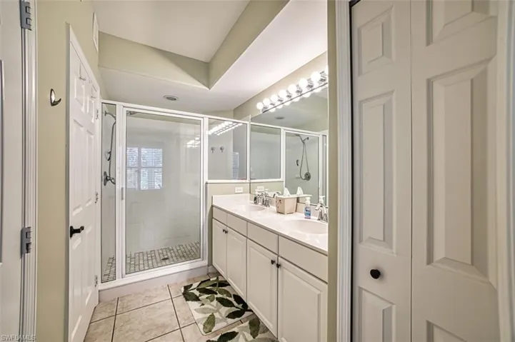 Bathroom with dual vanity, walk in shower, and tile patterned floors