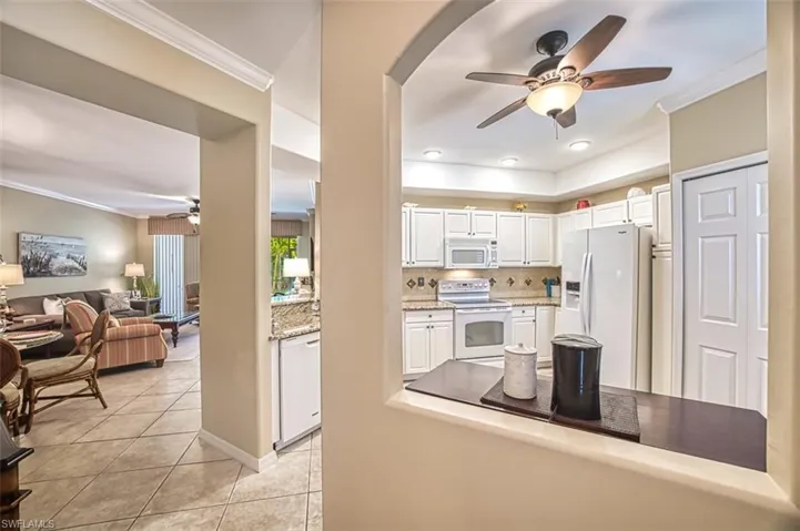 Kitchen with ceiling fan, white appliances, tasteful backsplash, and white cabinets