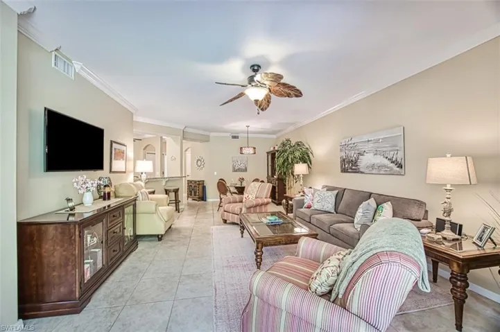 Tiled living room with crown molding and ceiling fan