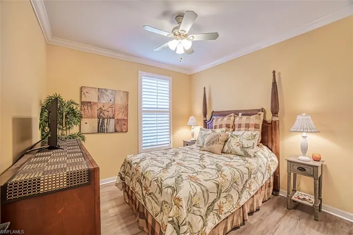 Bedroom featuring light hardwood / wood-style flooring, ornamental molding, and ceiling fan