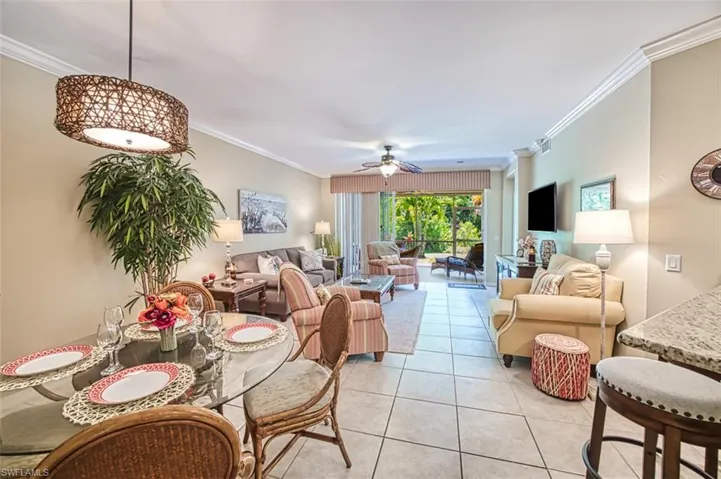 Living room with ornamental molding, light tile patterned floors, and ceiling fan