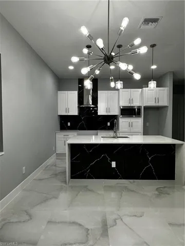 Kitchen with tiled island, custom cabinetry and backsplash and stainless steel appliances and oven hood
