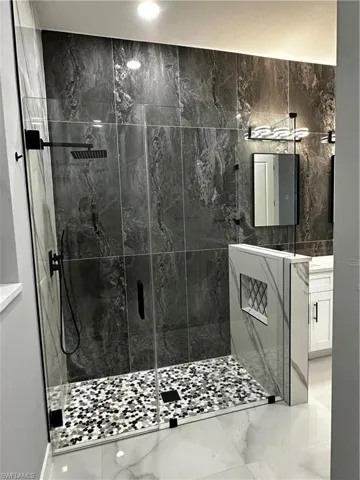 Custom glass shower with complete tiled walls, floor and niche