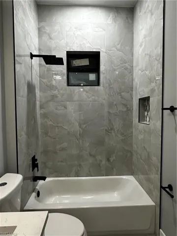 Custom tub in  shower with tiled walls and niche