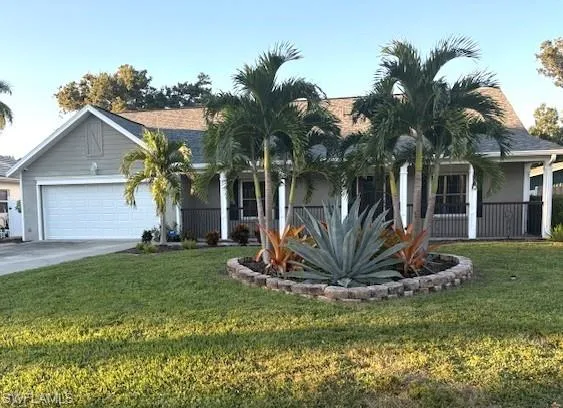 View of front of home featuring a front yard, driveway, an attached garage, and a porch