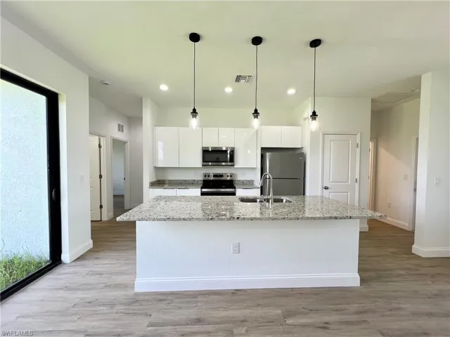 Kitchen featuring white cabinetry, light hardwood / wood-style flooring, appliances with stainless steel finishes, and sink