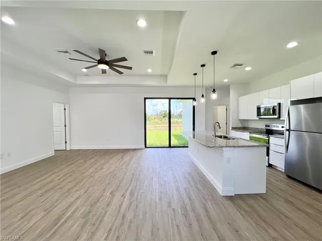 Kitchen with ceiling fan, white cabinets, light wood-type flooring, sink, and appliances with stainless steel finishes
