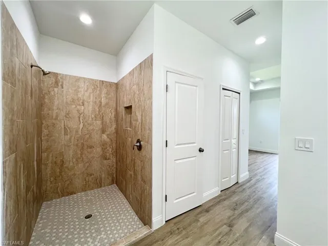 Bathroom with a tile shower and hardwood / wood-style floors