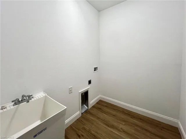 Clothes washing area with hookup for a washing machine, hookup for an electric dryer, hardwood / wood-style floors, and sink