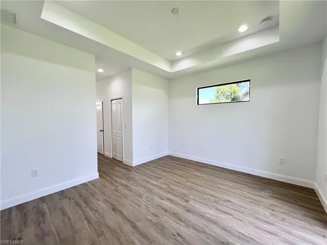 Empty room featuring wood-type flooring and a tray ceiling