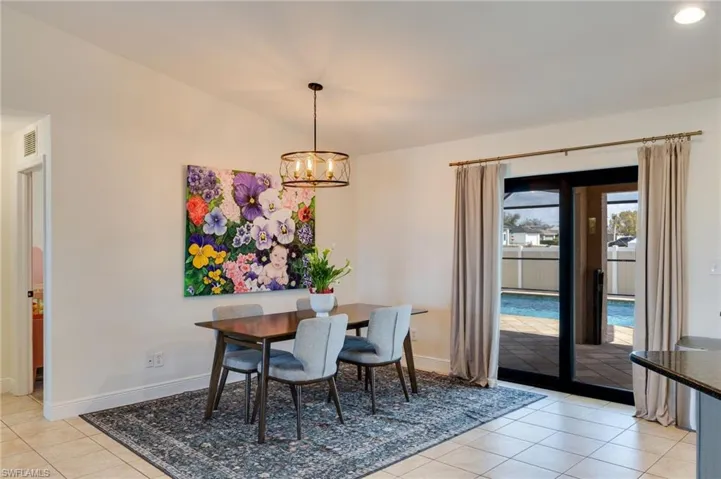 Dining room with light tile patterned flooring, vaulted ceiling, and suspended lighting