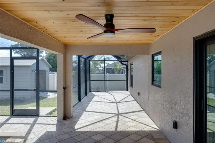 Unfurnished sunroom featuring ceiling fan, a patio, and healthy amount of natural light