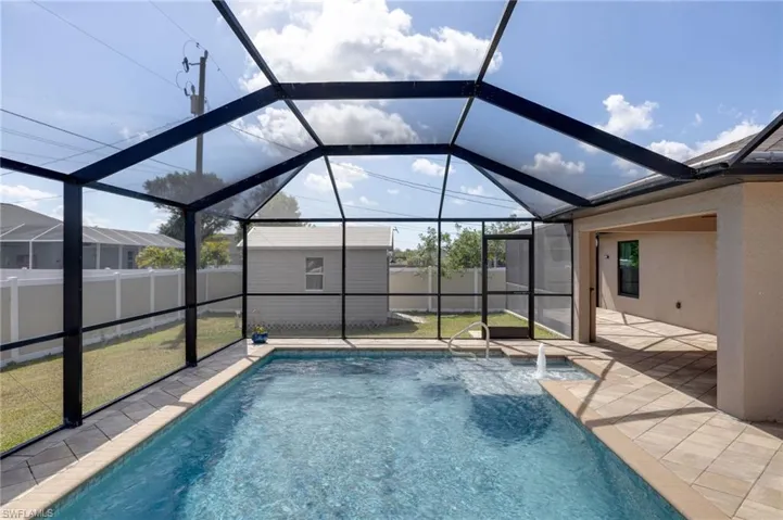 View of swimming pool featuring a lanai, a fenced backyard, a sunroom, and a shed