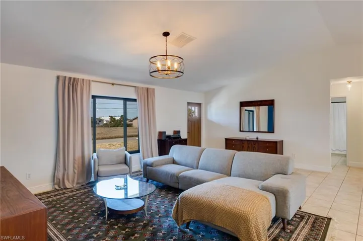 Living area with hanging lights, tile patterned floors, and vaulted ceiling
