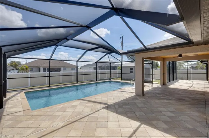 View of pool with glass enclosure, a fenced backyard, a sunroom, patio surround, and a shed