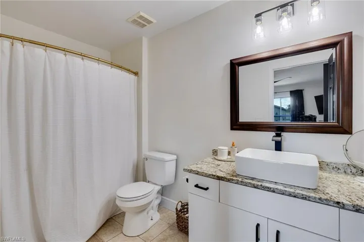 Full bathroom with vanity, light tile patterned floors, and a shower with shower curtain