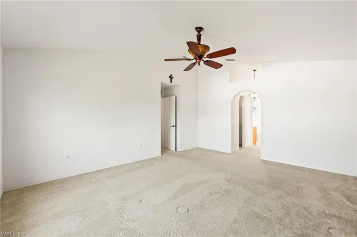 Master bedroom featuring arched walkways, light colored carpet, a ceiling fan, and vaulted ceiling