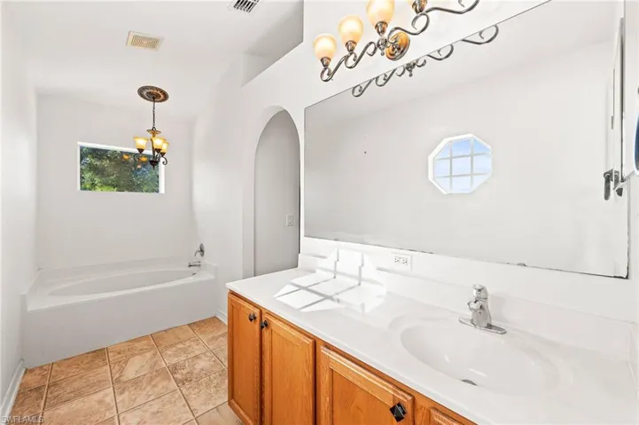 Bathroom with a garden tub, a chandelier, and vanity