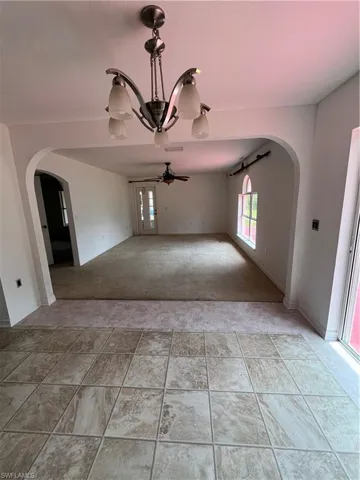Spare room featuring light colored carpet, arched walkways, and ceiling fan