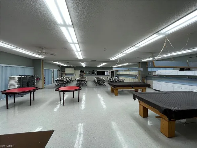 Recreation room featuring pool table, a ceiling fan, and a textured ceiling