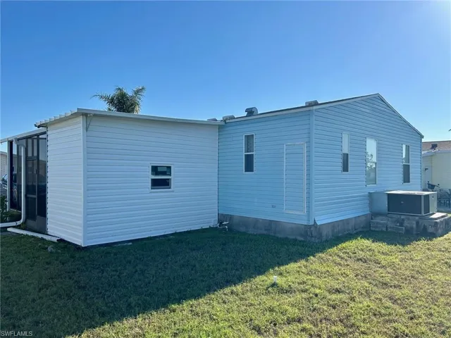 Rear view of property featuring a yard and central AC unit