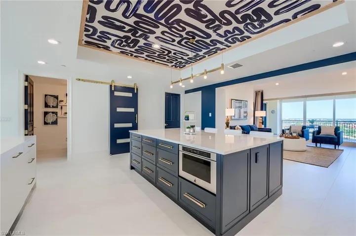 Kitchen with a raised ceiling, a barn door, light countertops, a kitchen island, and open floor plan
