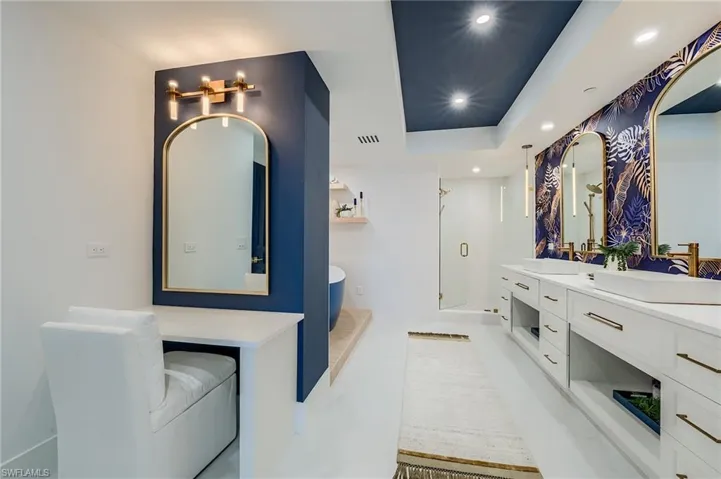 Full bathroom featuring a freestanding tub, double vanity, a stall shower, recessed lighting, and a raised ceiling